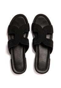 Sandalias negras con correas cruzadas de tela texturizada y suela negra lisa. Diseñadas sin parte trasera, con estilo de punta abierta.
