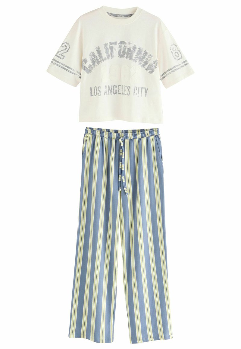 Hvid cropped t-shirt med teksten "CALIFORNIA 1982 LOS ANGELES CITY". Blå og gul stribet bredbensbukser med elastisk talje og snor.