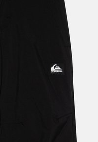 Μαύρες βερμούδες από ελαφρύ ύφασμα, με ραμμένο σχέδιο, πλαϊνές τσέπες και έντονη λευκή ετικέτα λογότυπου Quiksilver.