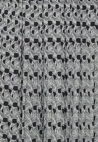 Tela en blanco y negro con un patrón de formas abstractas similares a hojas y cuadrados, superficie texturada, diseño plisado.