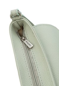 Angolo di una borsa in pelle verde menta con superficie texture, tirazip in metallo con il marchio "RYŁKO" e dettagli di cucitura bicolore.