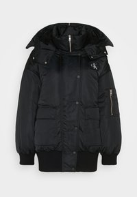 Chaqueta acolchada negra con un alto cuello, cremallera frontal, botones a presión, dos bolsillos frontales y un bolsillo en la manga con cremallera. Interior forrado de forro polar.