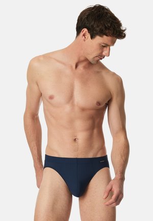 Diepblauwe zwembroek met ribbeltextuur, voorzien van een low-rise ontwerp en subtiele branding op de tailleband. Op maat gemaakte pasvorm voor comfort.