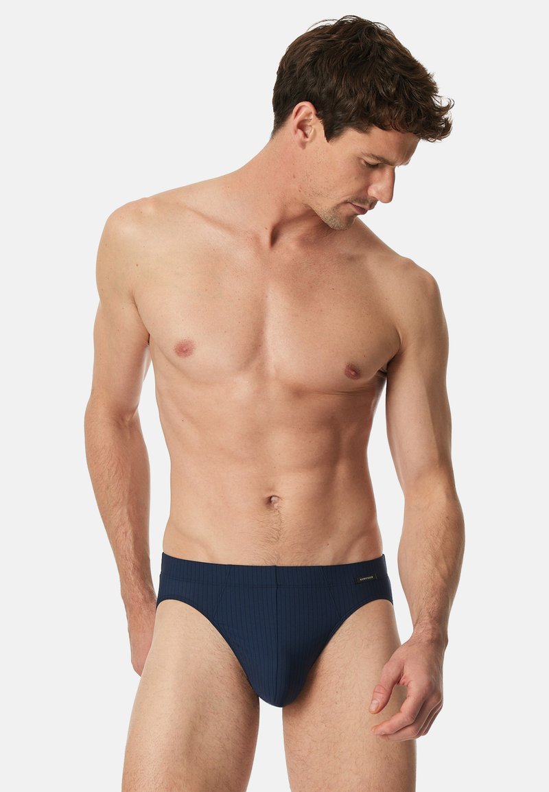 Marineblaue Badehose mit ribbed Struktur, mit einem niedrigen Bund und subtiler Markierung am Bund. Maßgeschneiderter Sitz für Komfort.