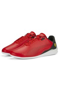 Czerwone skórzane buty sportowe o smukłym designie, z siateczkowymi akcentami, perforacjami oraz czarnym obcasem z żółtym logo. Biała podeszwa.