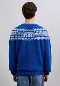 Suéter azul de punto con un canesú estampado en blanco. Presenta un dobladillo y puños acanalados. Textura suave y corte holgado.