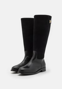 Botine negre până la genunchi, realizate dintr-un amestec de piele netedă și velur, cu un finisaj texturat, talpă plată și un mic buton decorativ.