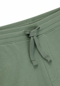 Groene katoenen sweatpants met een geribbelde tailleband, verstelbaar trekkoord en een zachte textuur. Beschikt over een zijzak en een eenvoudige uitstraling.