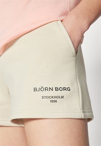 Svijetlosmeđi šorts s mekim zahvatom, s bočnim džepovima, rubom i crnim ispisanim tekstom: "BJÖRN BORG STOCKHOLM 1956."