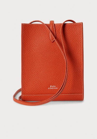 Oranžová kožená kabelka přes rameno s texturovaným povrchem, plochým dnem a tenkým popruhem. Na spodní části má malou značku.