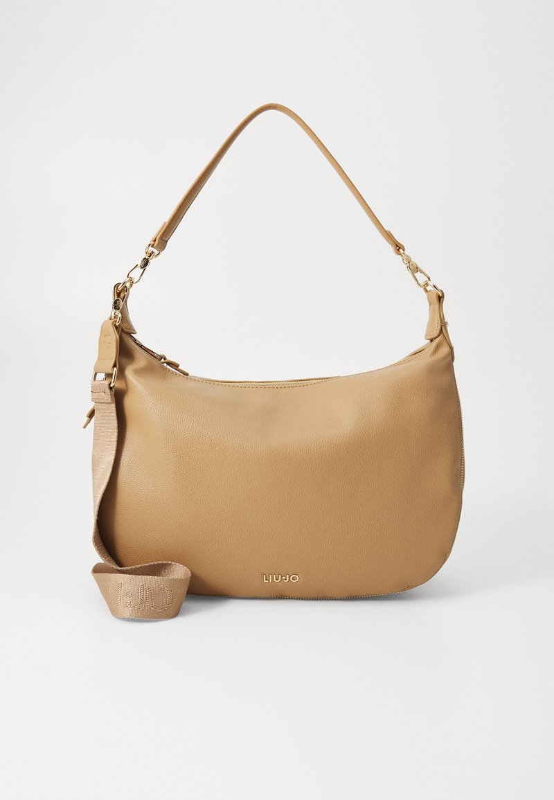 Sac à épaule en cuir beige avec une poignée courte, une bandoulière longue amovible et un petit logo métallique au centre avant.
