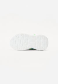 Semelle de basket en caoutchouc blanc avec un motif de grip texturé. Présente un dessus vibrant vert et bleu en matériau lisse avec un design courbé.