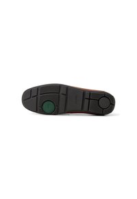 Suela de goma negra con patrones de agarre texturizados; presenta un acento circular verde y una marca. Diseño elegante y plano, ideal para varios estilos de calzado.