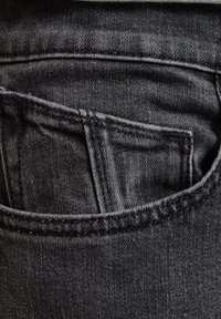 Material de mezclilla negra con un diseño de bolsillo trasero visible. La tela tiene una textura sutil y un ligero brillo.
