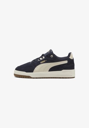 Marineblauwe en beige Puma lage sneaker met suède bovenwerk, vetersluiting en witte rubberen zool met detail van een gumzool.