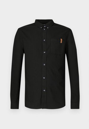 Mustast puuvillast pikemate varrukatega särk, millel on ees nööbitav osa, rinnatasku koos beežika aktsendiga ning sinised nööbid.