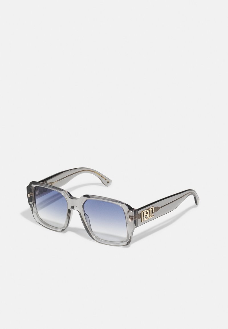 Ochelari de soare gri ombre cu o ramă rectangulară masivă, material transparent și detalii cu logo auriu pe braț.