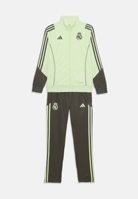 Groene en zwarte trainingsoutfit met een jack met rits en broek, voorzien van Adidas-strepen en het Real Madrid-logo. Gemaakt van een gladde, lichte stof.