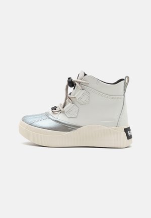 Fehér bőrből készült magas szárú sneaker, ezüst díszítésekkel, texturált talppal, szürke fűzőkkel és fekete logóval a sarkán.