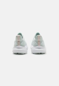 Lyseblå sneakers med en struktureret strikoverdel, hvid sål og bløde lyserøde detaljer ved hælen og tungen.