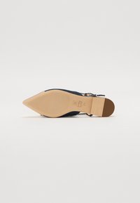 Chaussure en suede bleu marine à bout pointu, avec un talon fin, une semelle extérieure beige, et une sangle de cheville avec une boucle. Texture lisse avec des accents minimalistes.