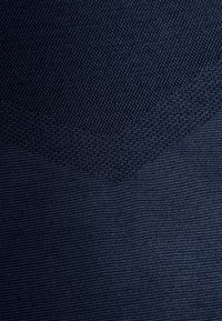 Marinblått tyg med en texturerad mönstring; har en slät sektion som smälter samman med en ribbad textur, vilket skapar visuell kontrast.