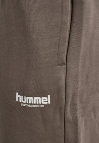 Braune Jogginghosen aus Baumwolle mit gerippter Textur. Versehen mit dem "hummel"-Logo in Weiß am Oberschenkel, mit Seitentaschen und einer entspannten Passform.