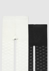 Dwie pary legginsów: jedne białe z teksturowanym wzorem w kokardki, drugie czarne z podobnym wzorem. Obie mają elastyczne paski w talii.