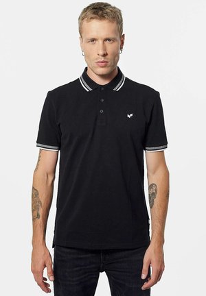 Polo noir avec un col à trois boutons, rayures blanches contrastantes sur le col et les manches, avec un petit logo sur la poitrine.