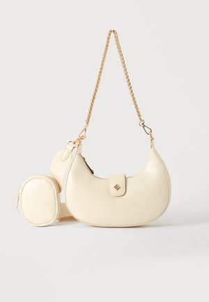 Borsa a mano color crema a forma di mezzaluna con tracolla a catena dorata e piccolo portafoglio ovale abbinato attaccato a una tracolla regolabile in tessuto beige.