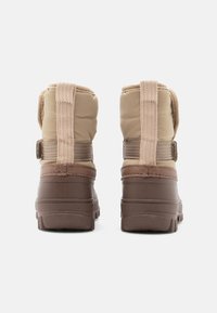 Botas de invierno aislantes en tono marrón claro con suelas de goma marrón, que presentan un material superior acolchado, correas removibles y un acabado texturizado para mayor agarre.