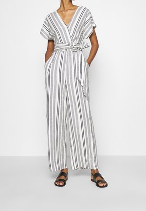 Lekki kombinezon w paski w odcieniach bieli i szarości; posiada kopertowy fason, krótkie rękawy, wiązany pasek oraz boczne kieszenie.