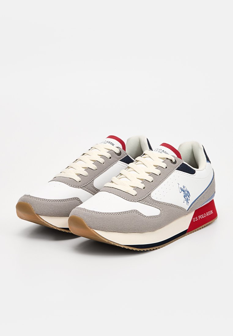 Zapatillas blancas y grises con acentos de gamuza, suela de goma, cordones crema, logo azul y detalles en rojo en el talón. Diseño atlético clásico.