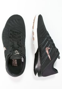 Mustat Nike Free 1.0 -kengät, joissa on kosketusteknologian verkkomateriaali, sulavalinjainen muotoilu ja metallinhohtoiset ruusukultaiset yksityiskohdat sivuilla. Valkoinen välipohja mustalla ulkopohjalla.