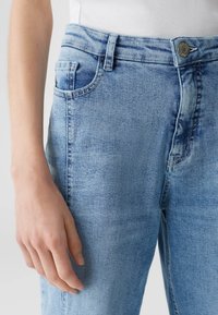 Jeans in denim azzurro chiaro con vestibilità rilassata, caratterizzati da un leggero effetto lavato, tasche frontali e chiusura con bottone metallico in vita.