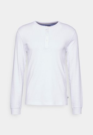 Hvid langærmet skjorte lavet af bomuld, med en henley-krave og tre knapper, ærmer med manchetter og en lige kant.