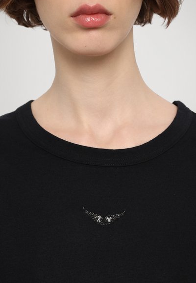 T-shirt en coton noir avec un col rond et un ornemente en strass décoratif en forme d'ailes sur la poitrine.