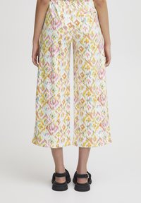 Pantalon blanc à jambes larges avec un motif abstrait coloré en rose, jaune et bleu. Taille élastique et une poche arrière unique.