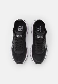 Svart sportskor med överdel i mesh, gummisula och tydlig Versace Jeans Couture-logotyp på tungan och sidan.