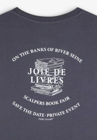 Marineblå bomulds-t-shirt med hvid trykt tekst og et billede af en stak bøger, samt buede tekstelementer og eventoplysninger.