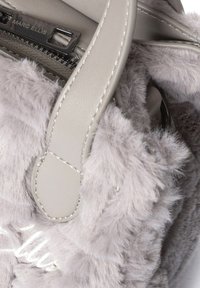 Grijze bonttas met een zachte, gestructureerde buitenkant en een glad leren handvat. Klein logodetail op de ritssluiting.