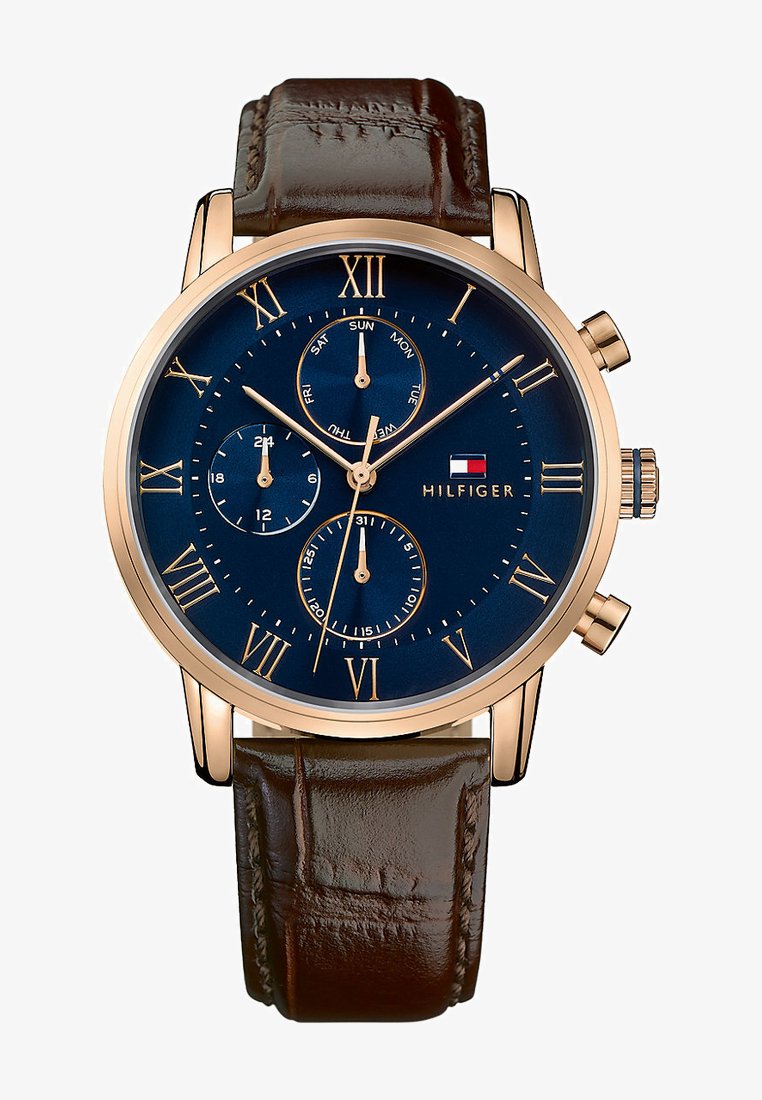 Relógio com bracelete de couro castanho, mostrador azul, algarismos romanos em dourado e funções de cronógrafo. Inclui indicadores de data e dia.
