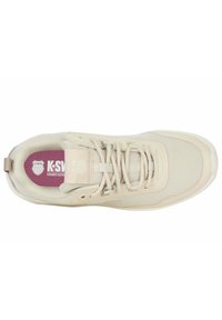 Zapato deportivo color crema con materiales de malla y sintéticos, punta redonda, parte superior texturizada y plantilla rosa etiquetada como "K-Swiss Court Style."