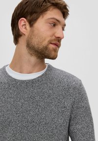 Szary, teksturowany sweter z okrągłym dekoltem i białą wewnętrzną kołnierzykiem, ozdobiony dzianinowym wzorem. Materiał ma miękki, przytulny wygląd.