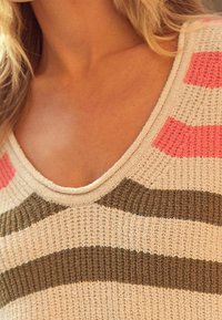 Knit sweater featuring horizontal stripes in pink, olive green, and cream, with a wide V-neck and textured fabric.