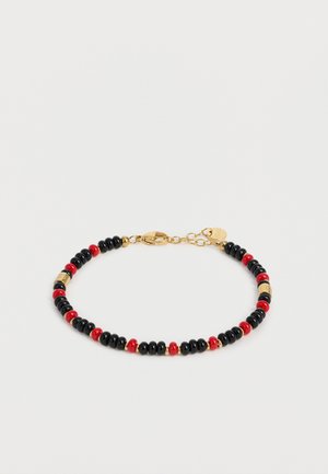 Bracelet avec des petites perles rondes noires et rouges alternées, des perles intercalaires dorées et un fermoir mousqueton doré avec chaînette d’extension.