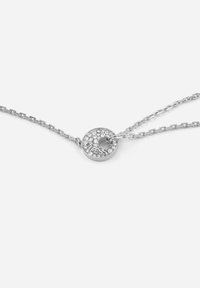 Collana d'argento con un pendente circolare, caratterizzato da una superficie testurizzata decorata con piccoli cristalli trasparenti e un centro vuoto. Il design della catena è a maglie.