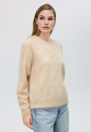 Maglione beige e morbido a maglia con scollatura rotonda e maniche lunghe, abbinato a jeans in denim blu chiaro. Tessuto soffice con vestibilità comoda.