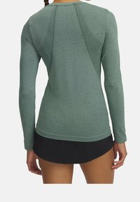 Maglia sportiva a maniche lunghe in tessuto verde tenue con un motivo testurizzato, dotata di un comodo scollo rotondo e dettagli delle cuciture a contrasto.