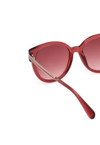 Röda cat-eye solglasögon med gradientlins. Transparent båge, eleganta guldaccent på armarna och slät yta. Den böjda formen förbättrar designen.